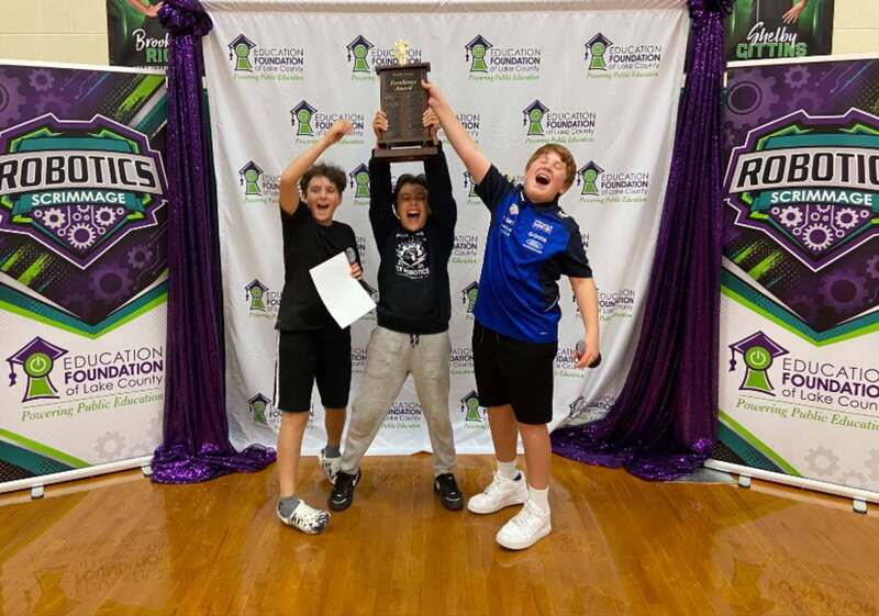 students pose with award in front of Education Foundation of Lake County signage