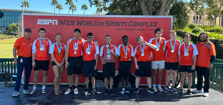 Student athletes posed and smiling. Some are wearing medals. One is holding a trophy. Wording in background says, "ESPN Wide World of Sports Complex, Walt Disney World Resort"