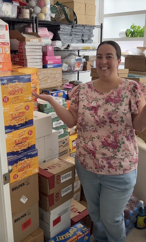 Meagan Dewitz standing in front of boxes of donated food items