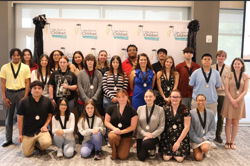 Take Stock in Children 2025 graduates posed in front of branded backdrop