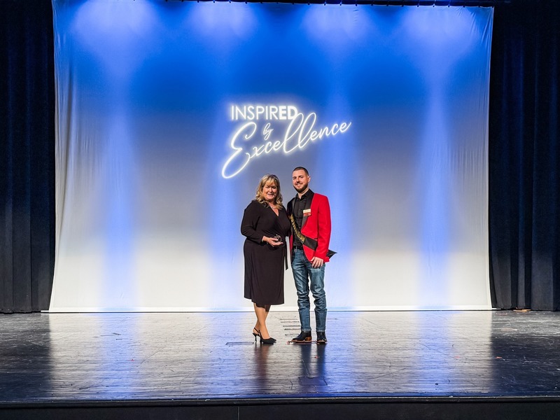 Trevor Misegades stands on stage with Deanna Thomas, Lake Tech Executive Director