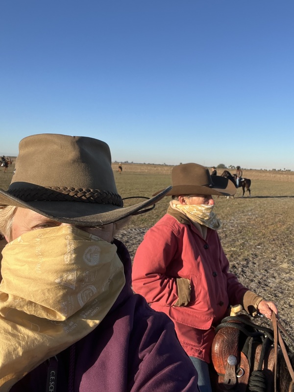 Two women on horses with bandanas covering their faces