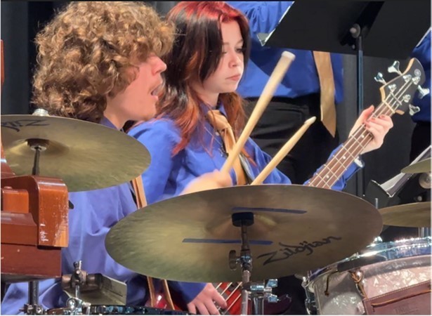 Drummer and guitarist in matching blue shirts