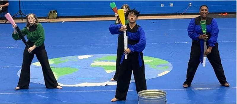 Four winterguard performers standing in pose