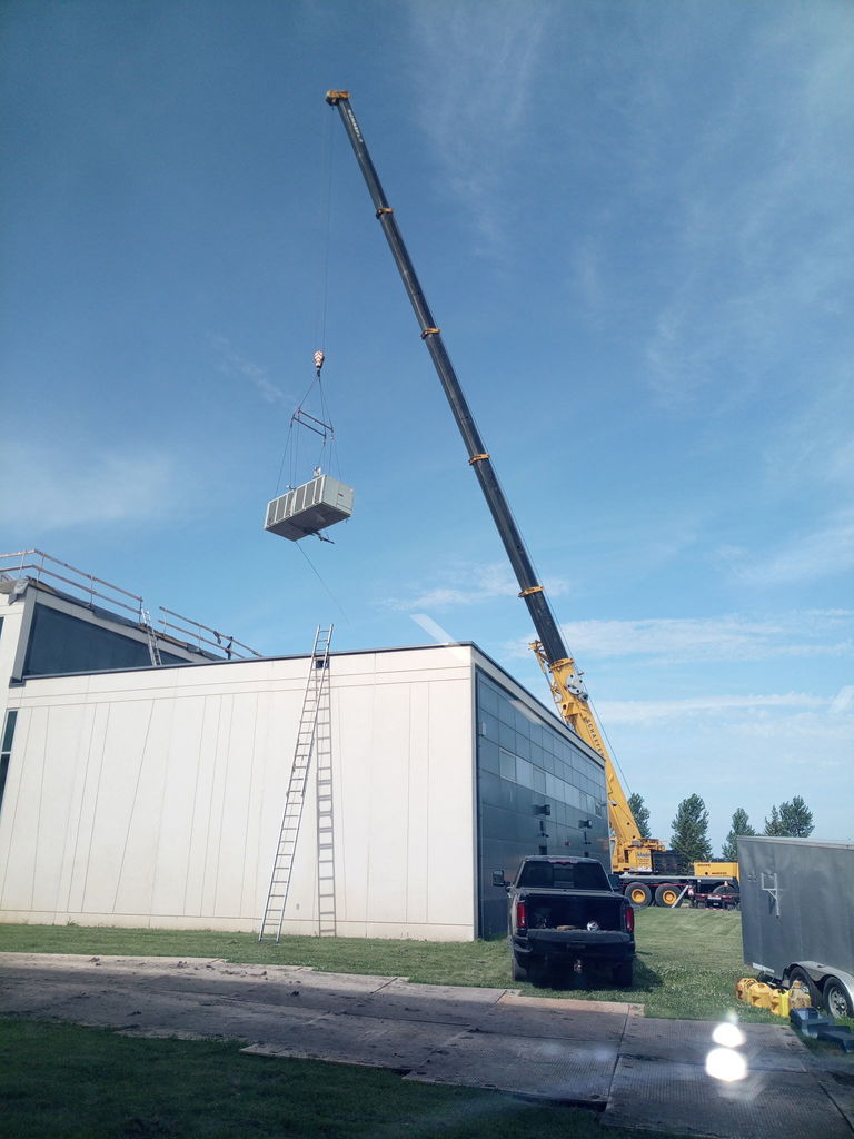 crane moving an AC unit on to the roof.