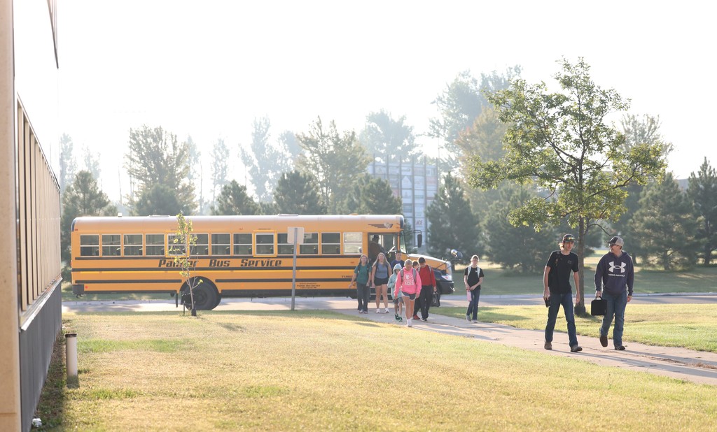 Students getting off the bus and walking in to school.