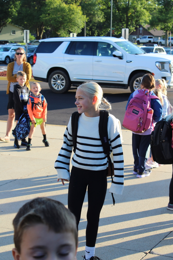 little girls walking into building holding backpack.