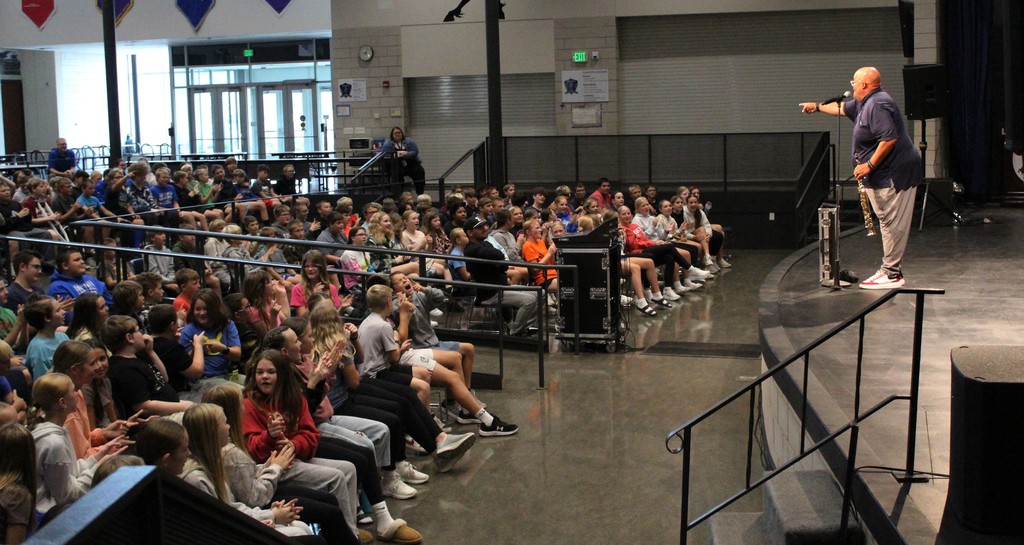 Reggie Dabbs standing on stage speaking to an auditorium of students.