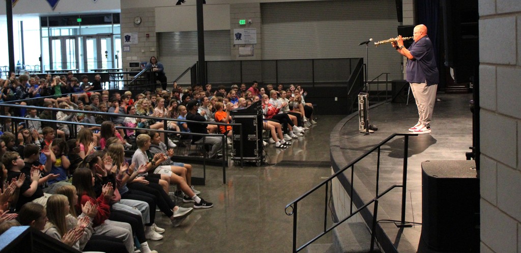 Reggie Dabbs playing soprano saxophone with students watching in auditorium.