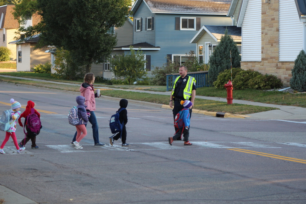 students crossing the street with the help of local law enforcement.