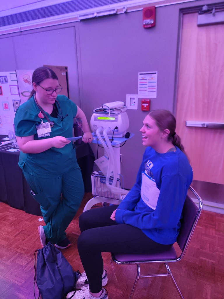 Student sitting in a chair and having a nurse look at vitals.