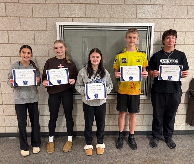 Students posing in front of a sign holding their certificates.