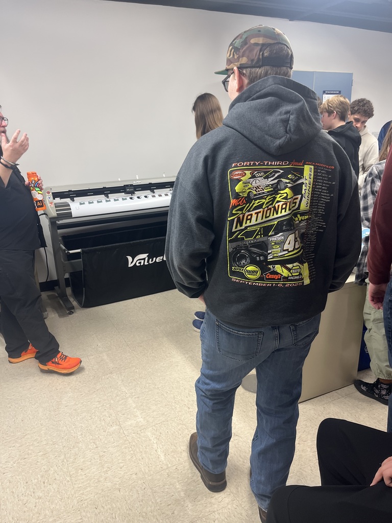 Students watching a printer print stickers. 
