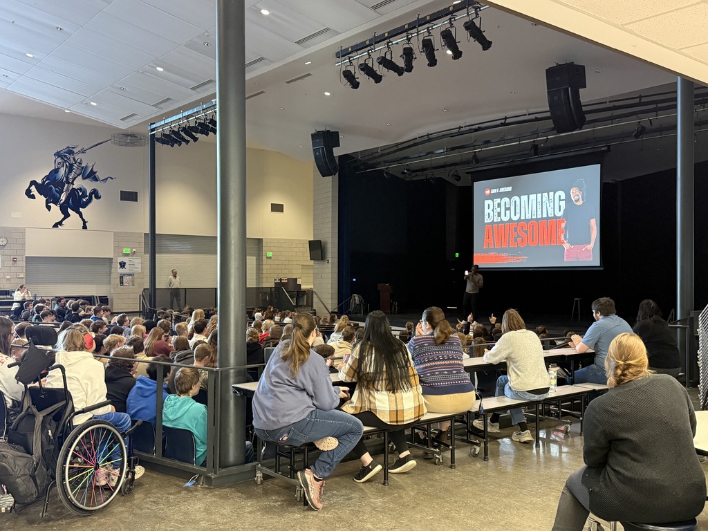 students sitting in the cafetorium listening to Cam F. Awesome. 