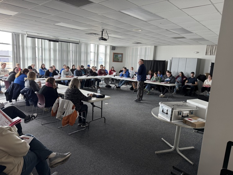 secondary staff members sitting and listening to instruction in open room