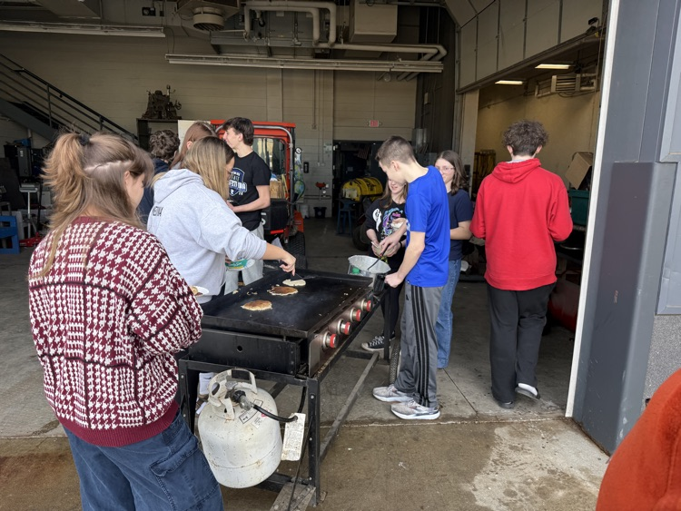 students frying pancakes on a griddle 