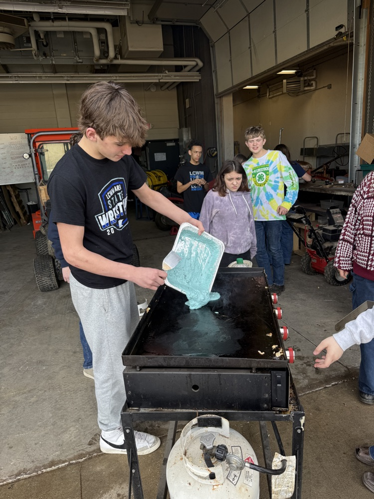 students frying pancakes on a griddle 