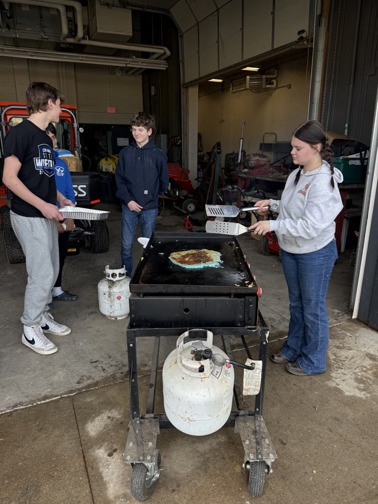 students frying pancakes on a griddle 