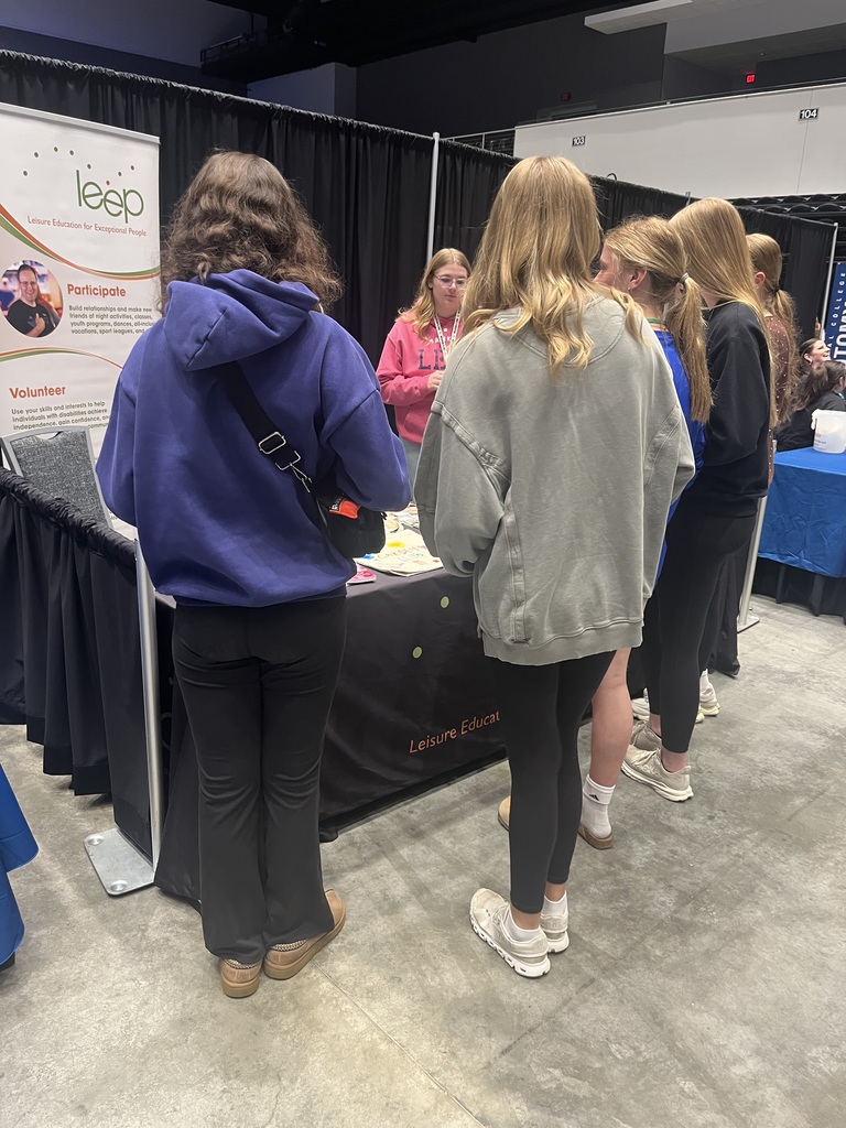 girls standing in front of a table talking to a representative from LEEP.  