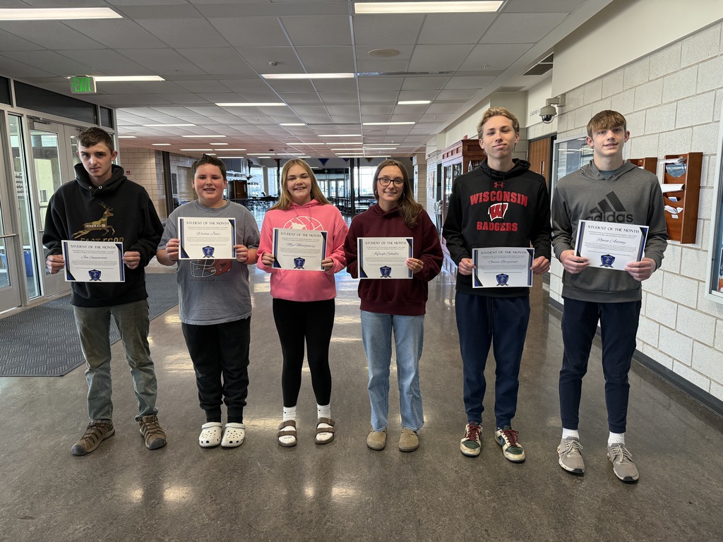 students standing in a line holding their certificates for student of the month.