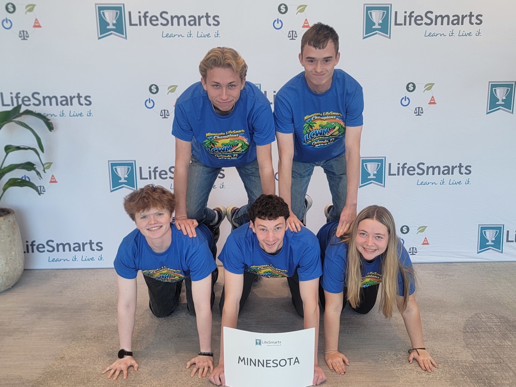 Students in a pyramid on the floor holding a MN sign in front of a backdrop that says lifesmarts all over it.