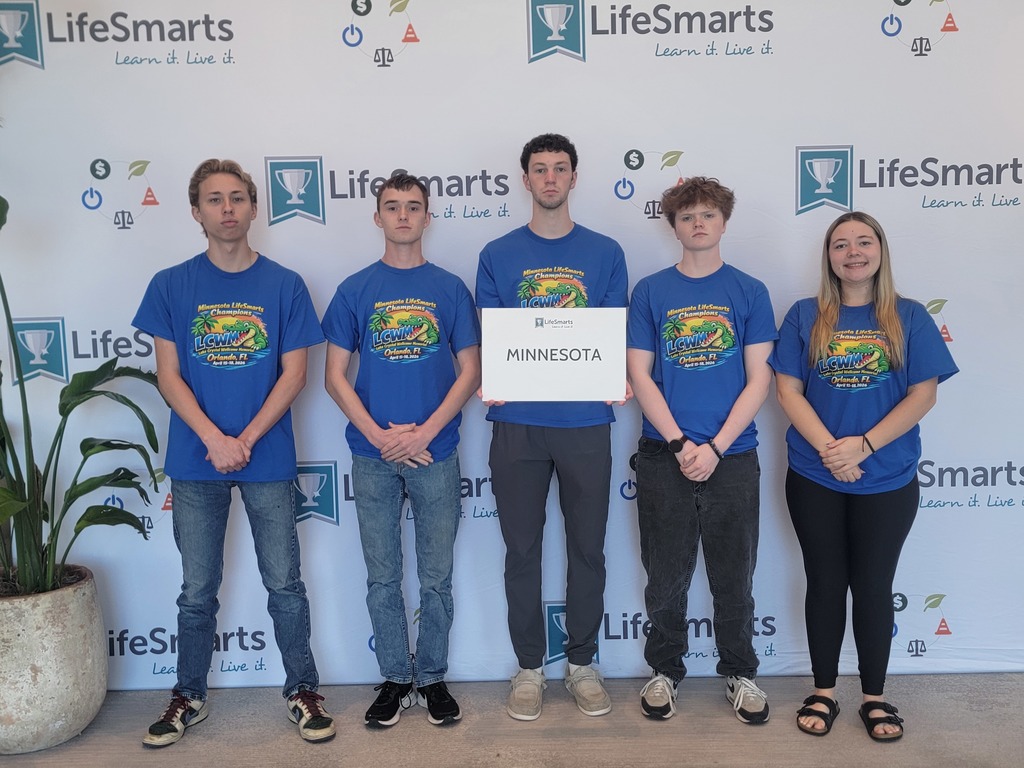 Students posing somberly holding a sign that says MN in front of a Lifesmarts backdrop.  