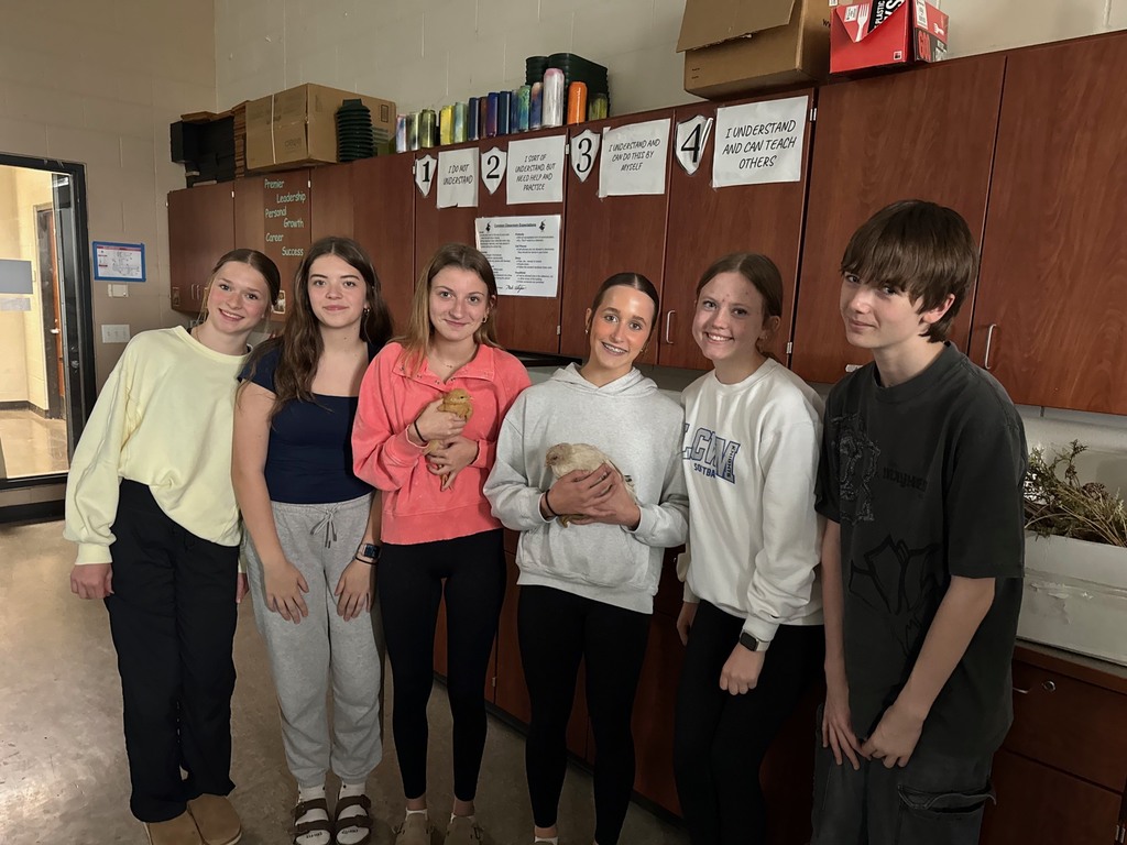 group of students holding two chickens in classroom. 