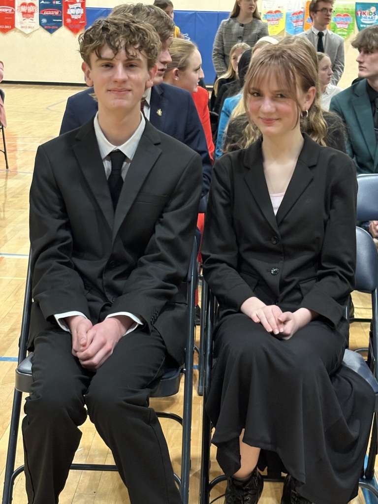 Ryan and his sister, Aherly, seated in chairs in a school gym, smiling at the camera.  