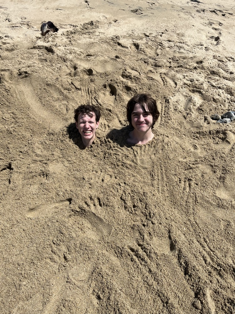 two students buried in sand 