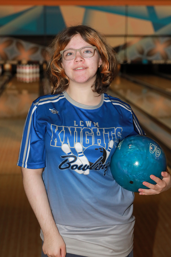 Student holding a bowling ball on her hip in the bowling alley.