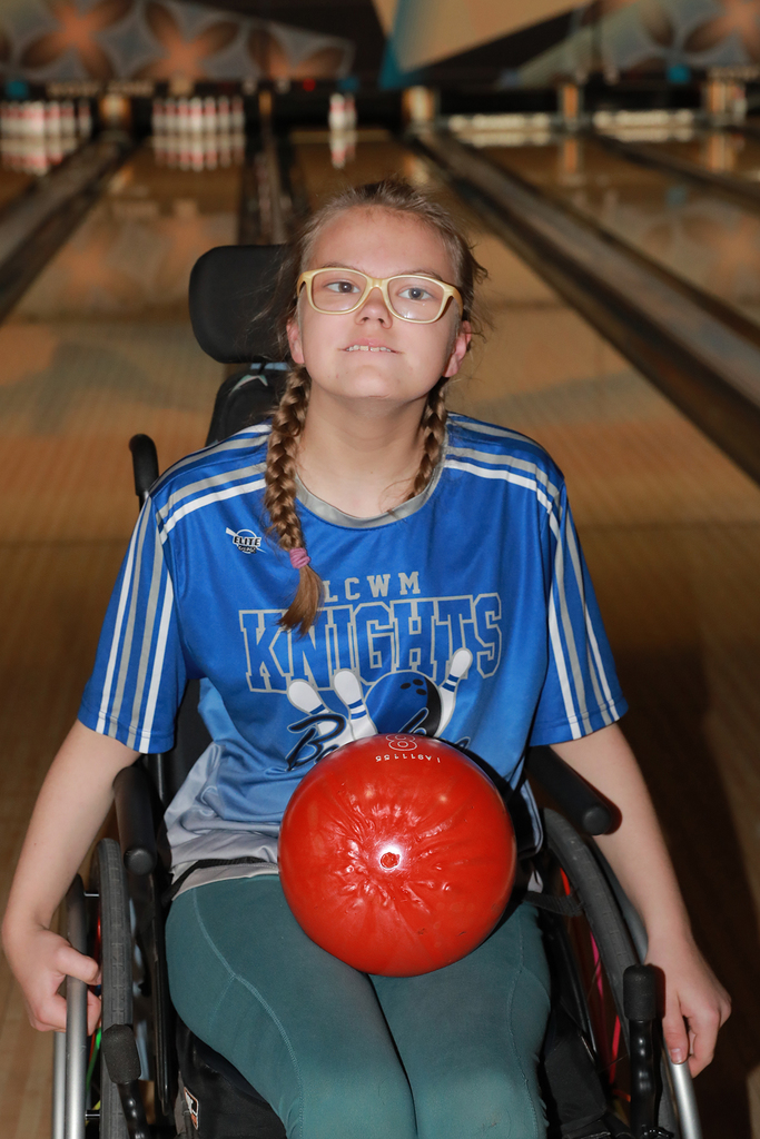 Student holding a bowling ball in her lap while sitting in her wheelchair.