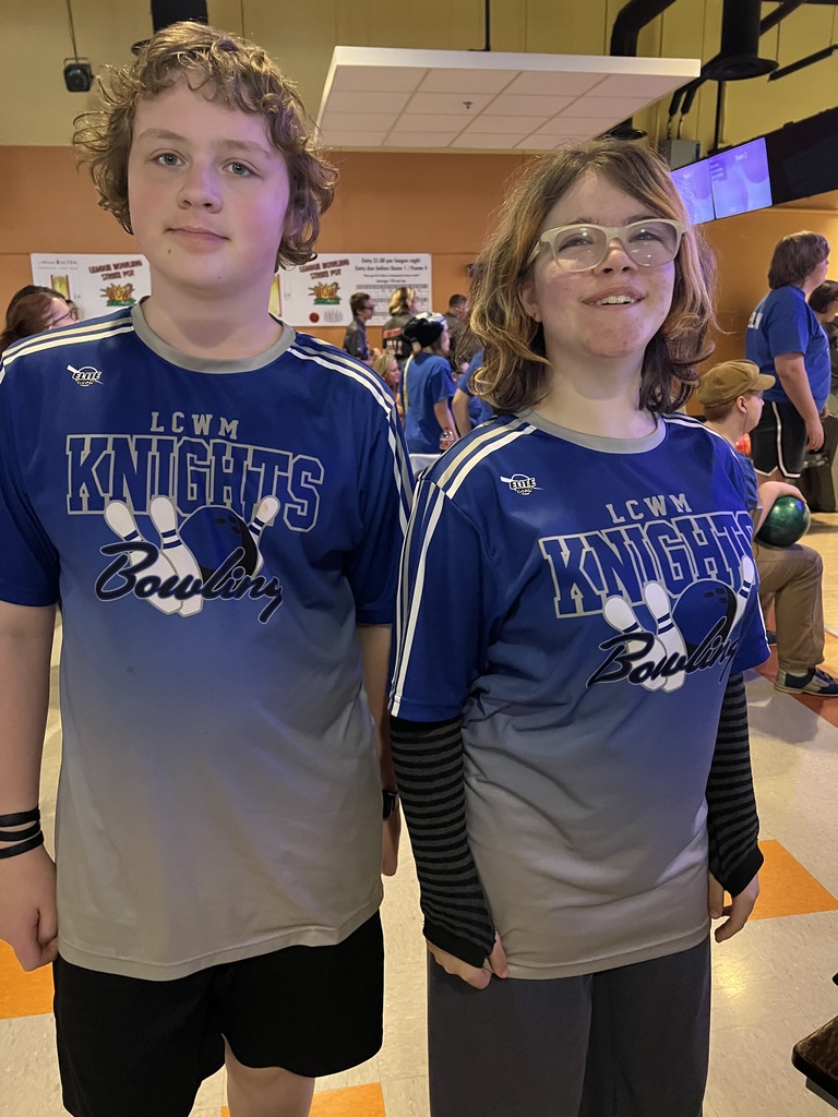 Two students standing next to eachother in the bowling alley. 