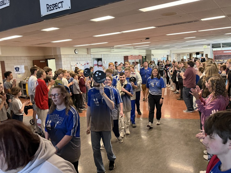 students lined up in two lines while bowling students walk through the middle of them. 