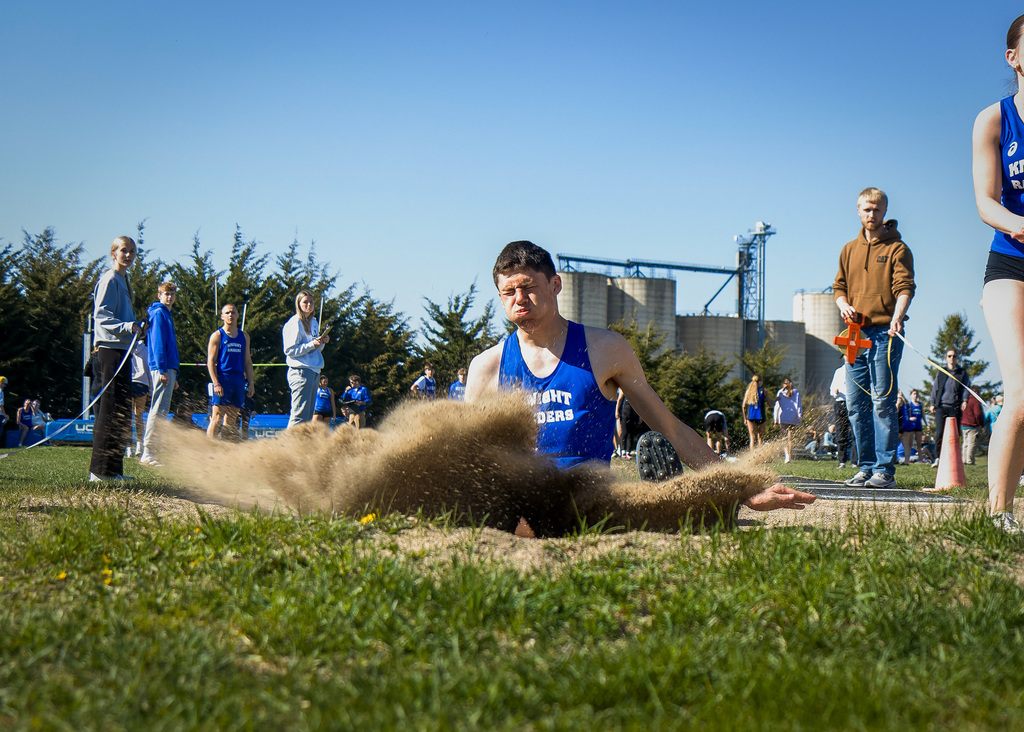 Student landing in the sand pit with sand flying.