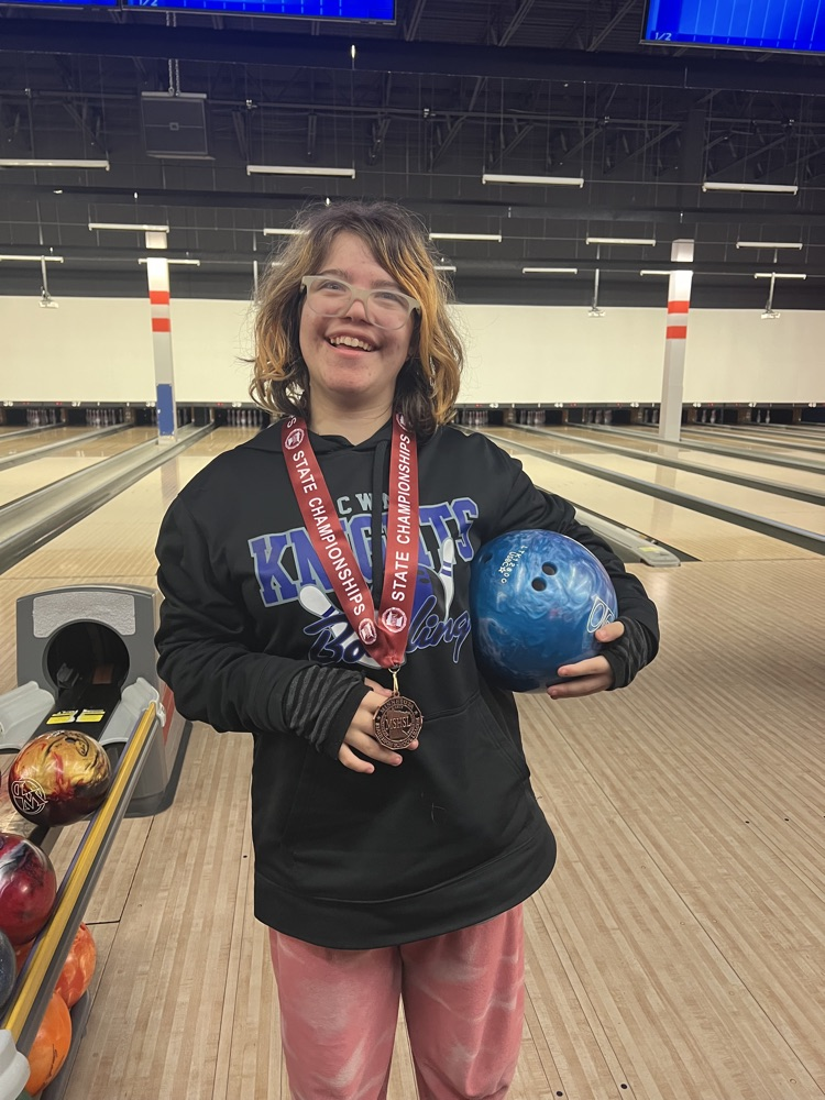 student holding bowling ball in the bowling alley smiling at camera  