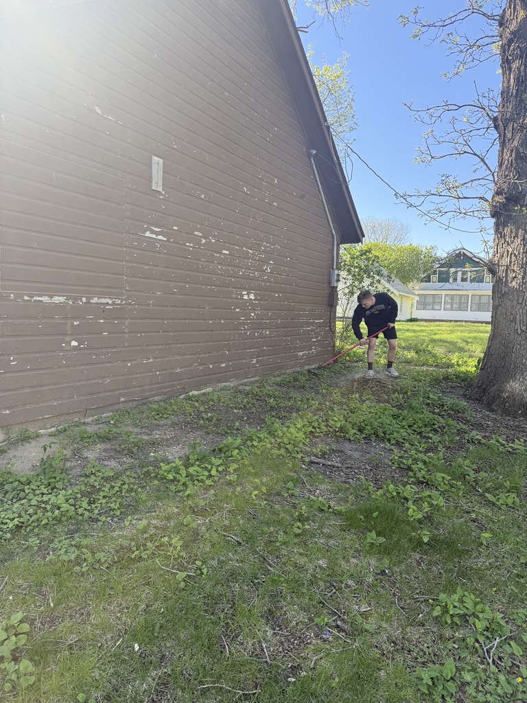 student raking along the back side of a building.  