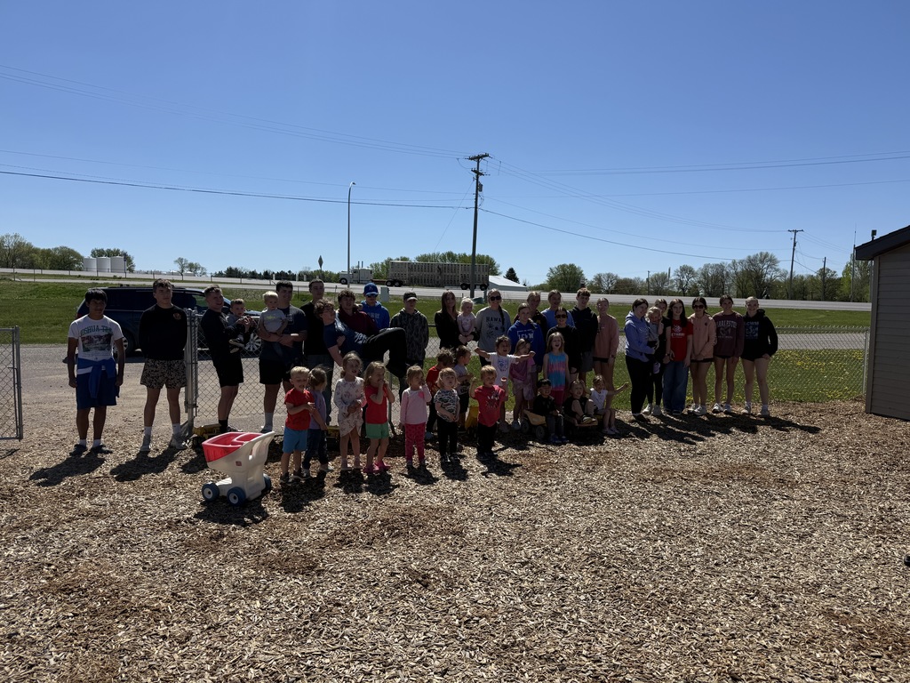 Students lined up along a fence with little daycare kids standing next to them at the daycare center in town.