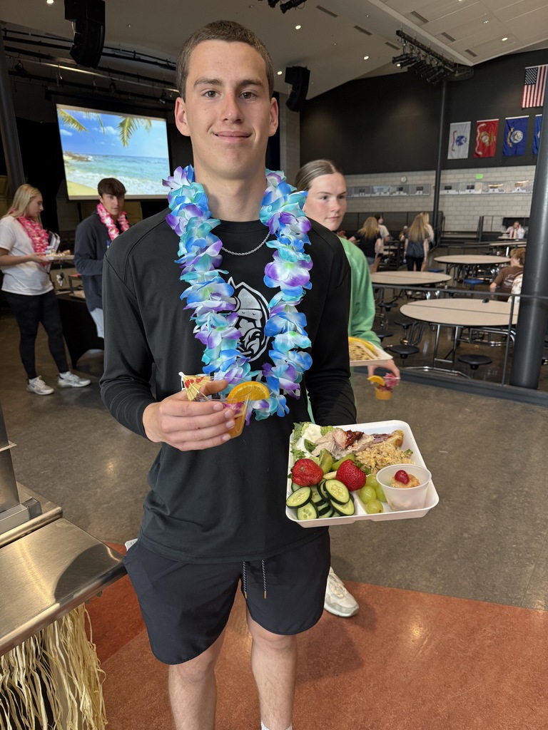 High School student holding a tray of food with the lunch luau.  