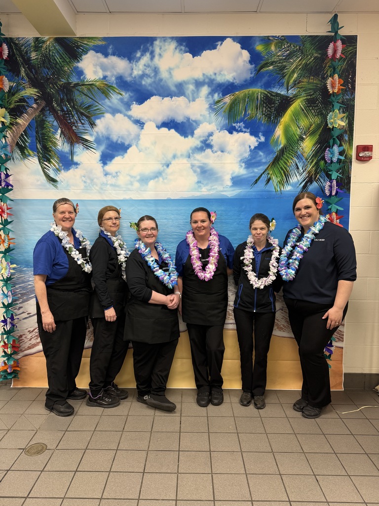 Lunch ladies standing in front of a hawaiian themed background, beach scene.
