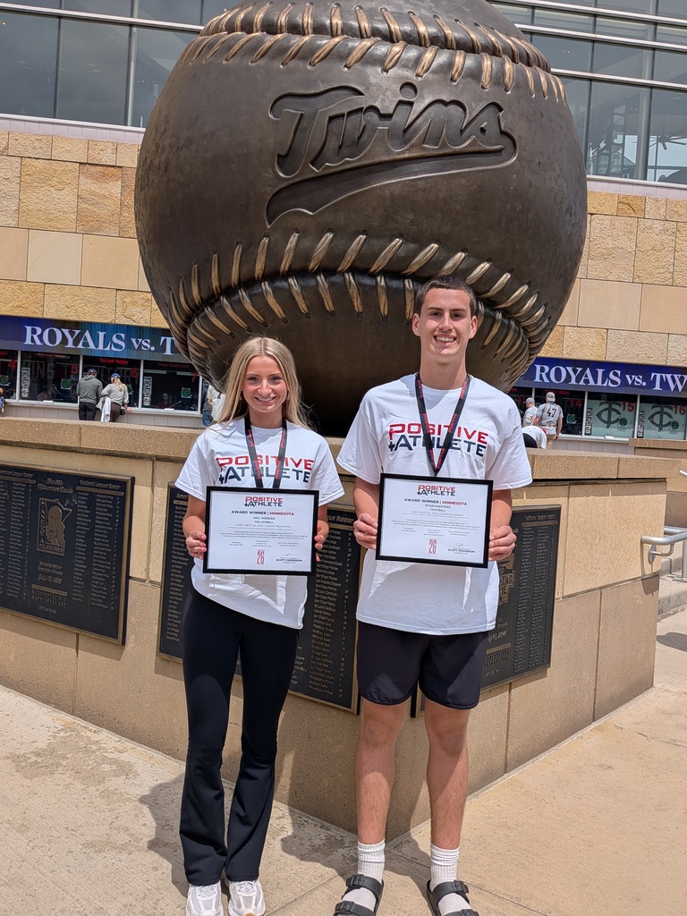 Positive Athlete Award winners, Jaci and Ryan, standing in front of the Twins Stadium brass baseball statue.