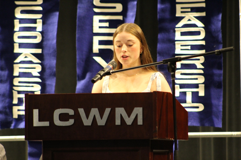 student standing behind a podium speaking into a microphone.