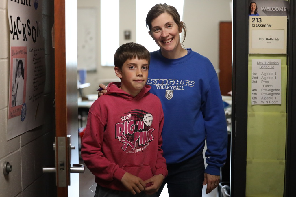 student and teacher standing in classroom door smiling. 
