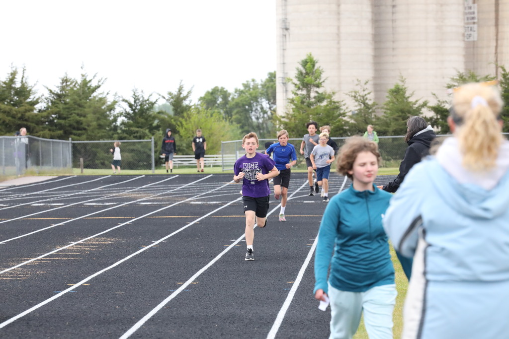 Boy running down the track with others on his heels, chasing him down.