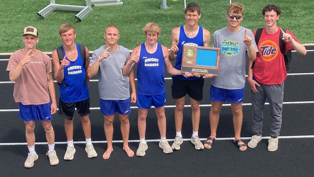 Boys standing in a link on a track holding up one finger like #1.  Two boys are also holding a trophy.  