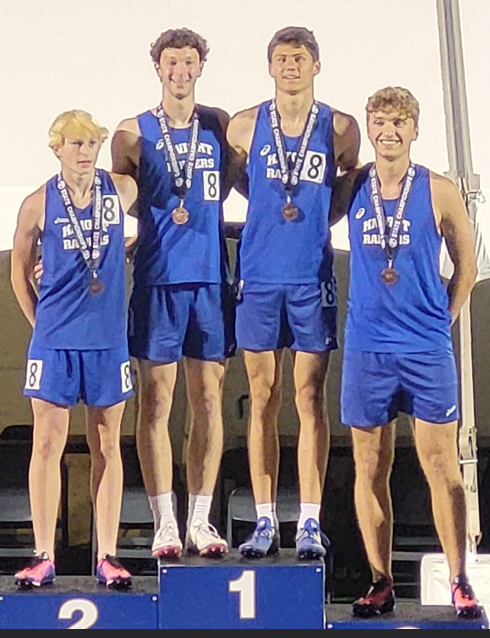 4x4 standing on a podium with medals on smiling at the camera. 