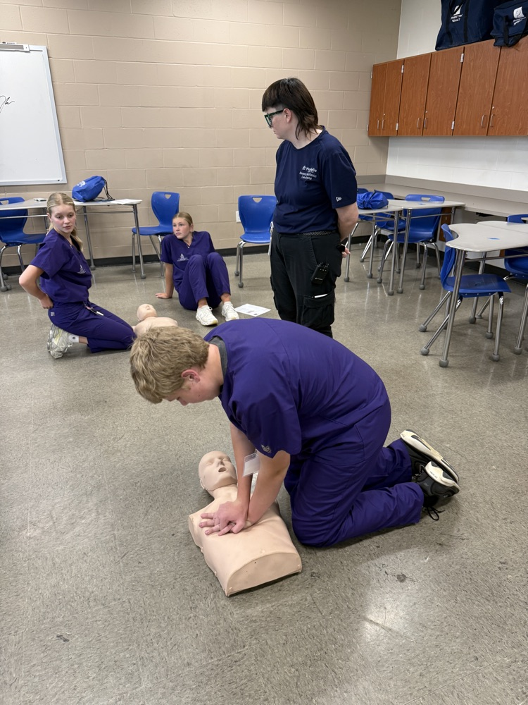 students in classroom looking at “dummies” for CPR. 