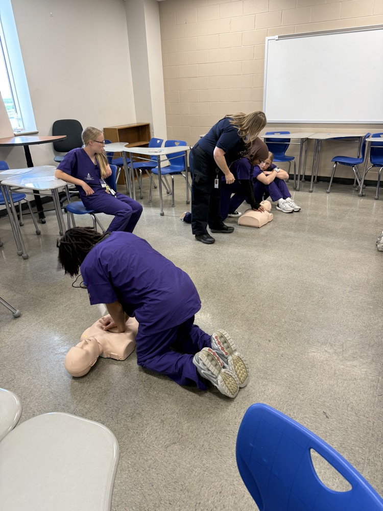 students in classroom looking at “dummies” for CPR. 