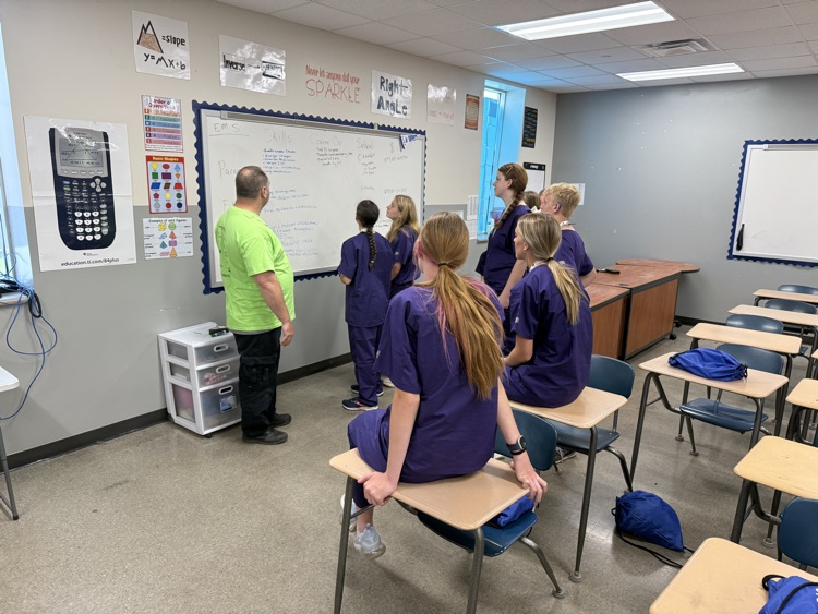 STUDENTS IN CLASSROOM LOOKING AT WHITE BOARD LISTENING TO INSTRUCTION. 