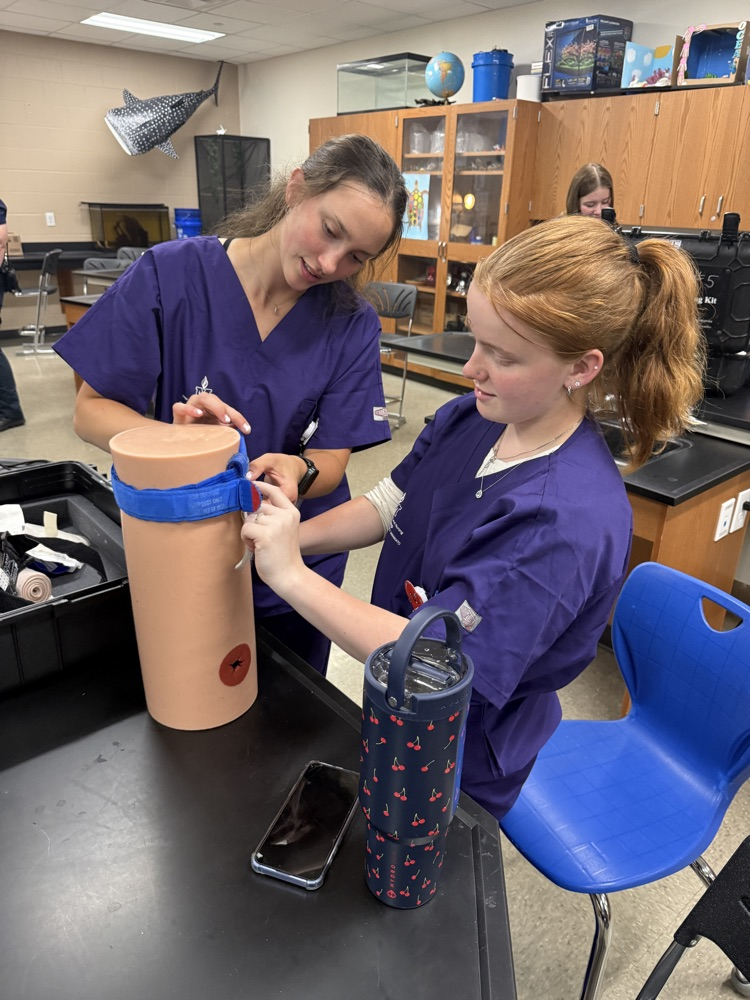 STUDENTS PRACTICING PACKING A WOUND. 
