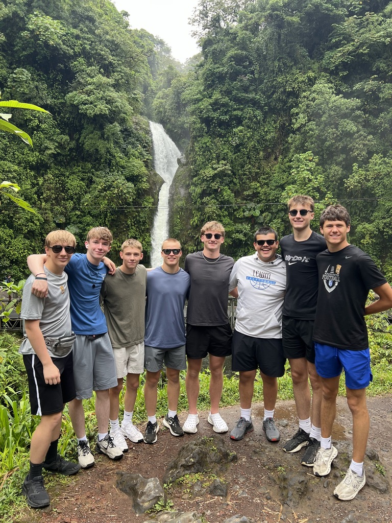 students standing in front of a waterfall.
